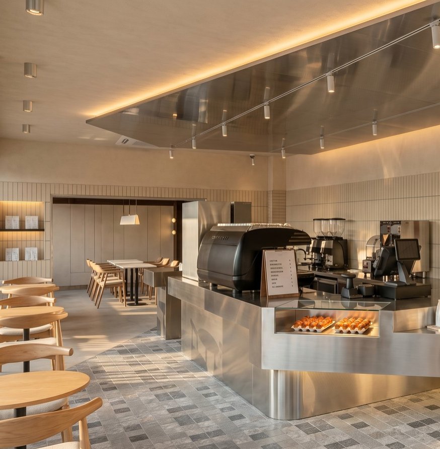 Close-up of the espresso machine and grinder counter with a stainless-steel canopy overhead