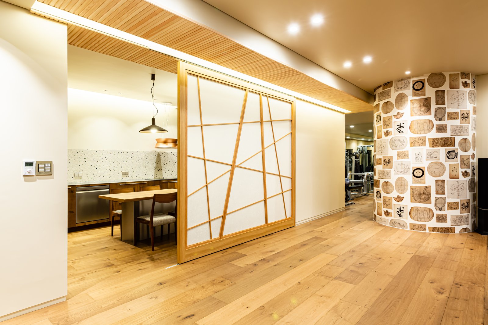 Wood-framed sliding door with geometric muntins opening from a hallway into the kitchen and dining nook