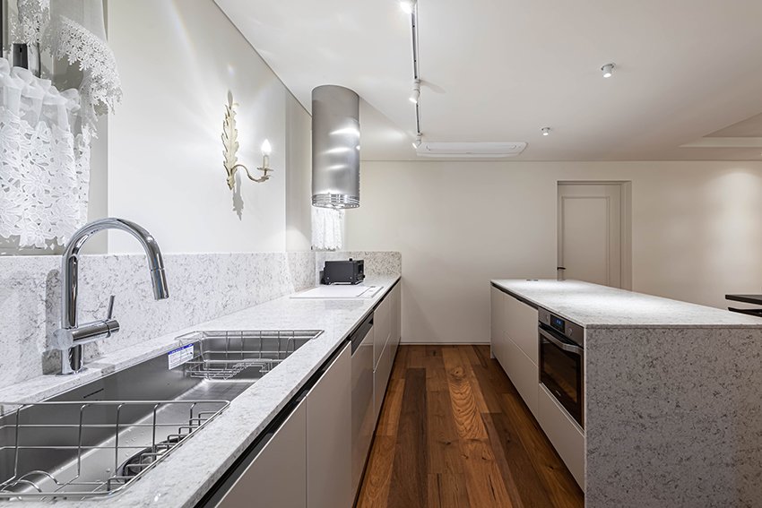 Kitchen counter with granite countertop, stainless steel sink, and cylindrical range hood