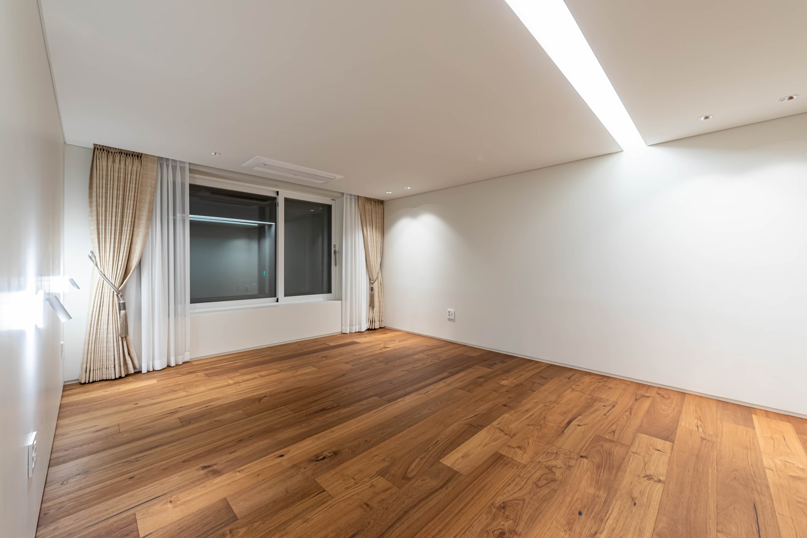 Empty bedroom with sheer and blackout curtains beside a window