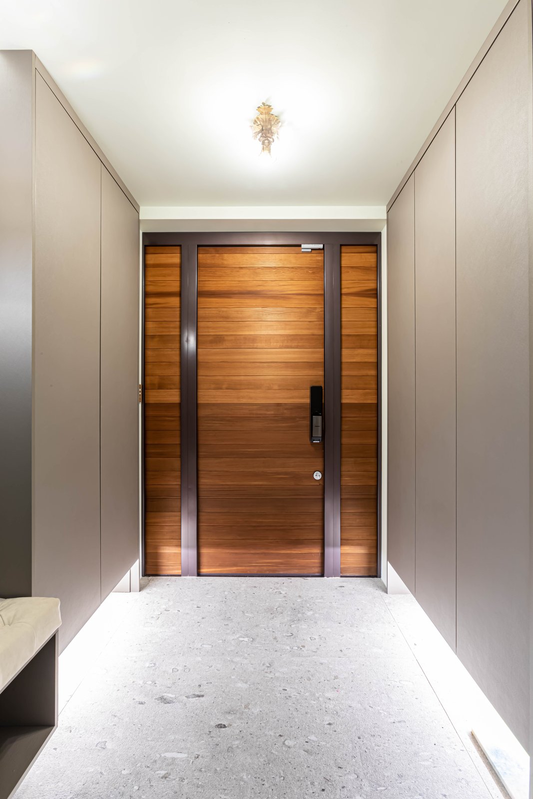 Entry door in warm wood slatting with dark metal frame and matching side panels