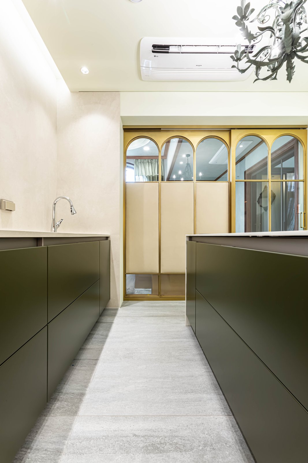 Kitchen corridor with arched brass-framed glass doors beside the marble island