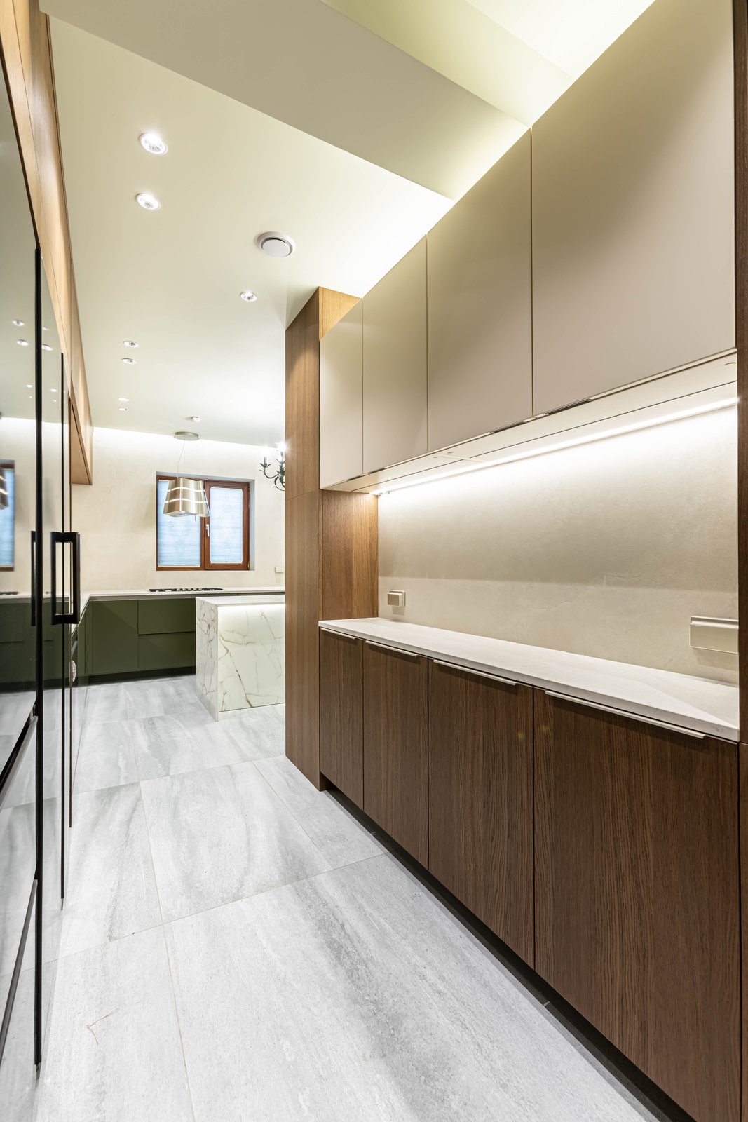 Kitchen corridor with dark wood cabinetry reflected in a mirrored panel