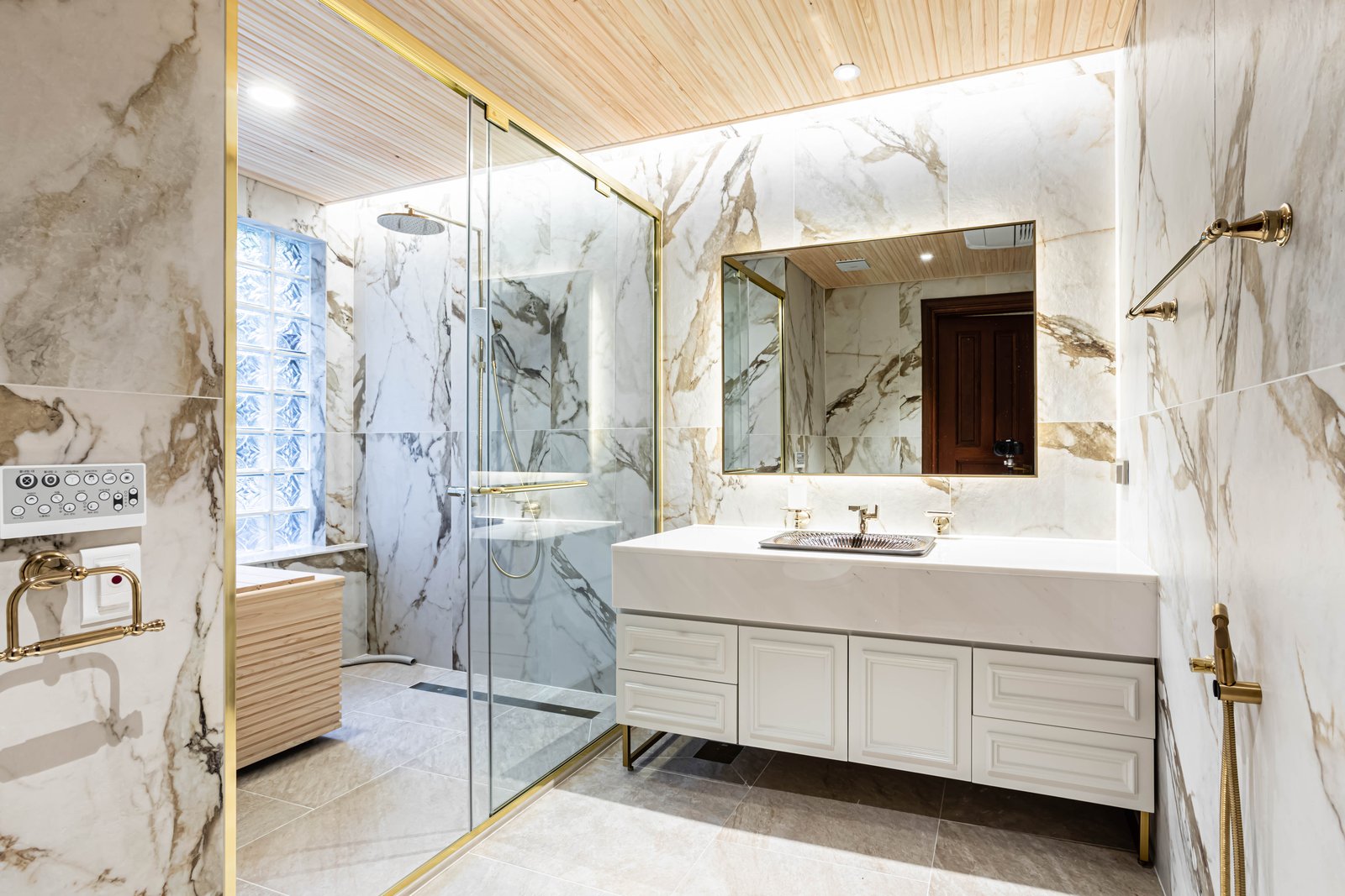 Marble bathroom with glass shower enclosure and brass fixtures