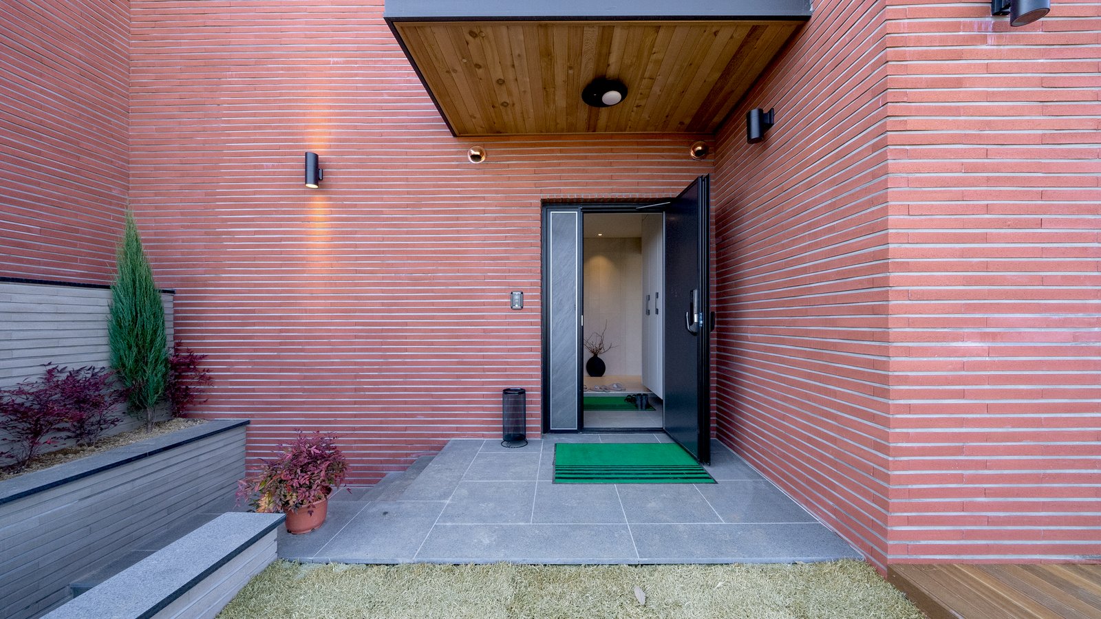 Entry door under a wood canopy with brick facade and stone patio