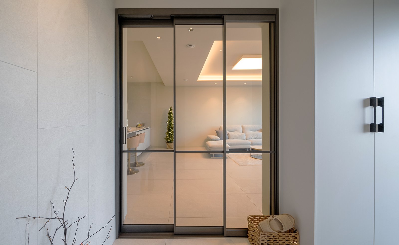 Living room viewed through open glass sliding doors from the entry, kitchen beyond
