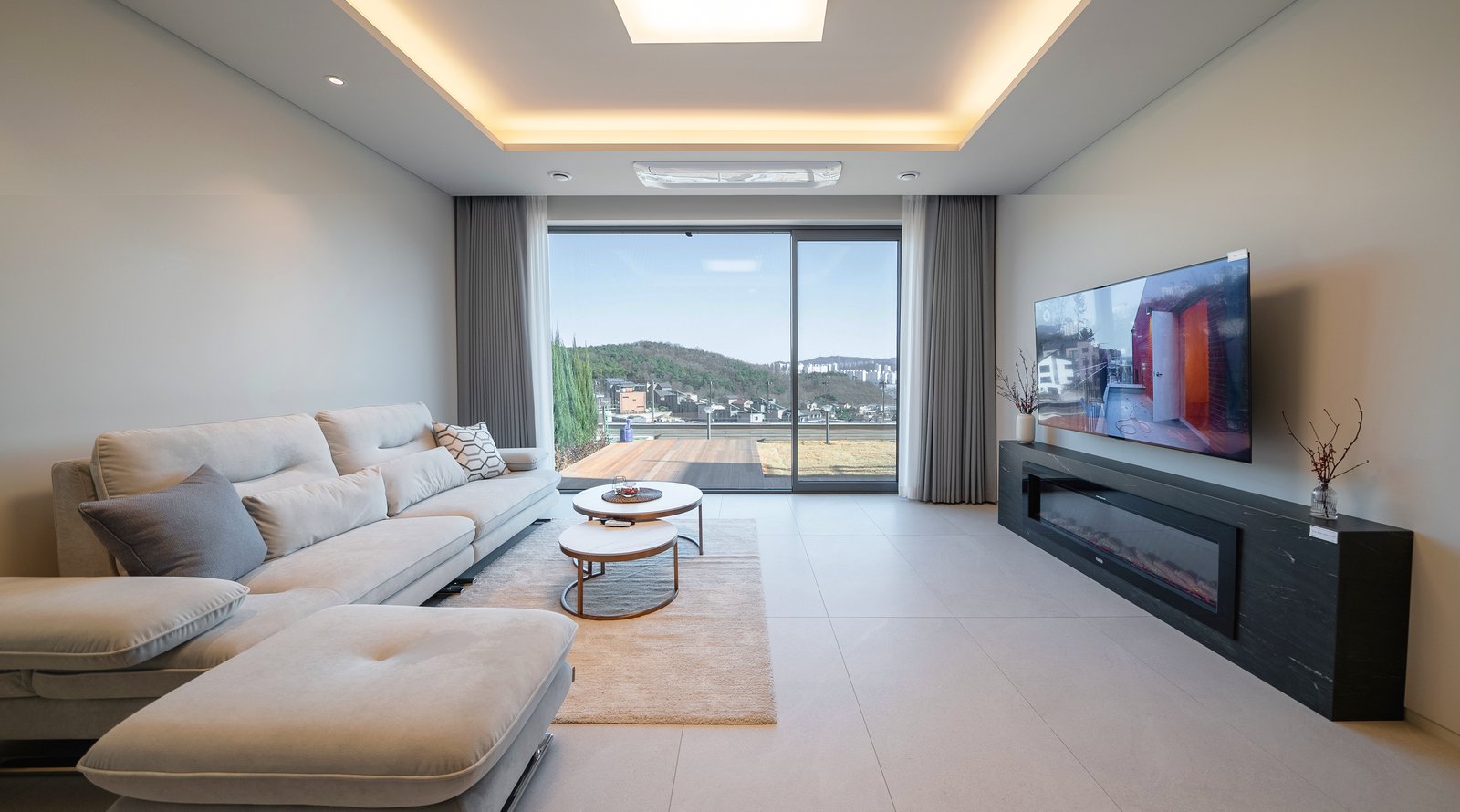 Living room with gray sofa, round nesting coffee tables, and a wall-mounted fireplace beside a glass sliding door