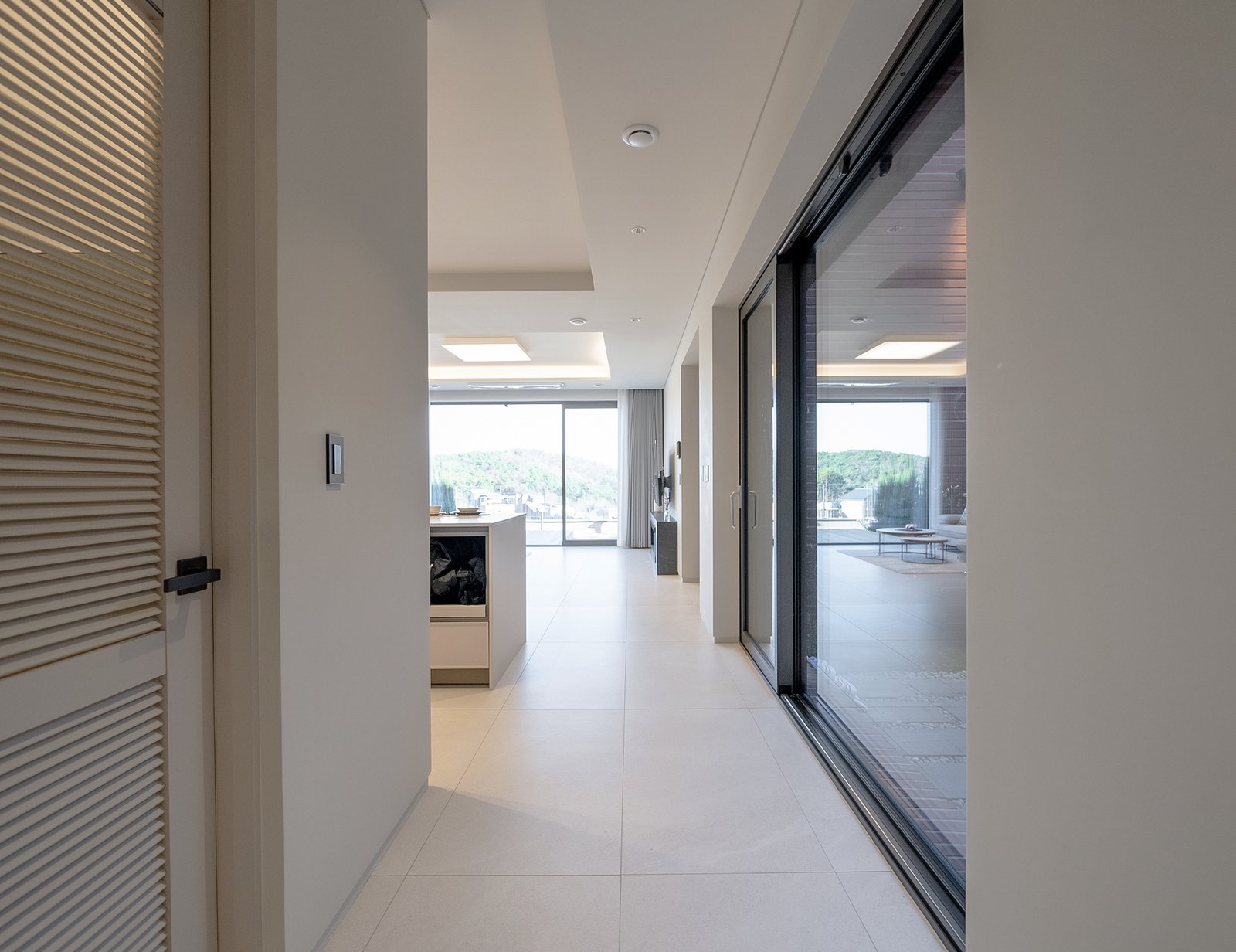 Hallway view from the kitchen toward the living room and glass sliding doors to the terrace