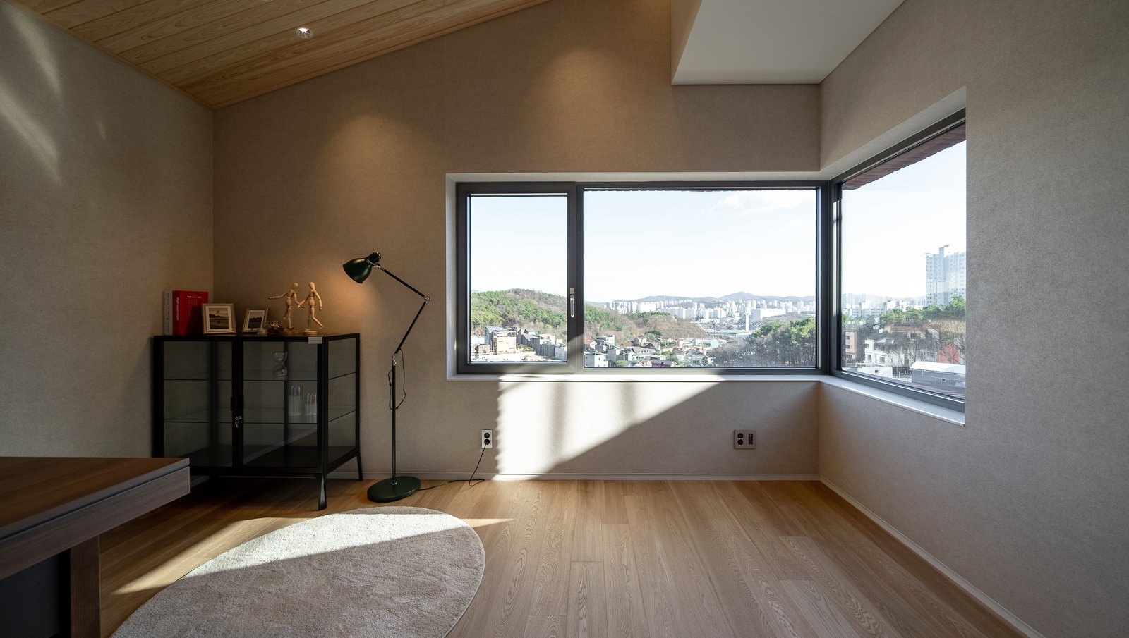 Bedroom with a pitched wood ceiling, corner windows, desk lamp, and glass display cabinet