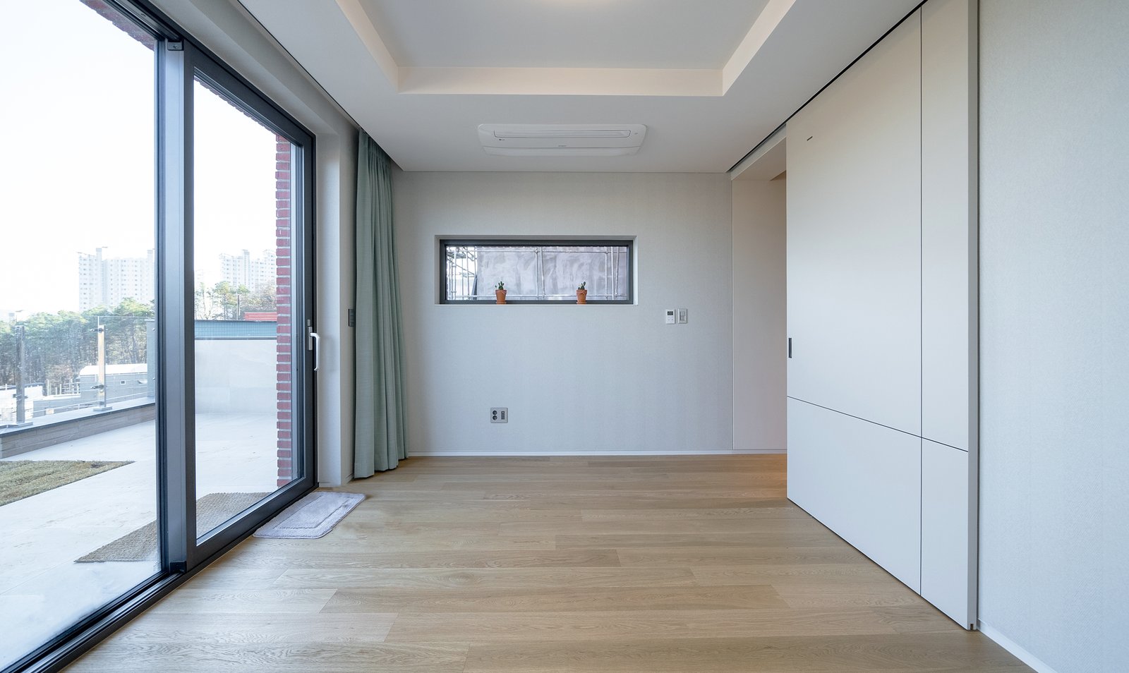 Bedroom with a glass sliding door to an outdoor terrace and sage-green curtain