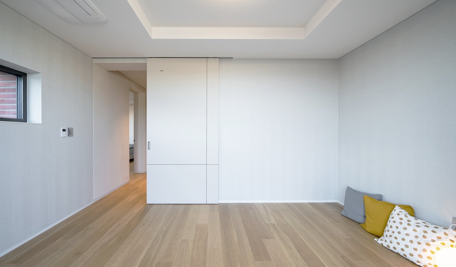 Bedroom with a white built-in sliding wardrobe and colorful pillows in the corner