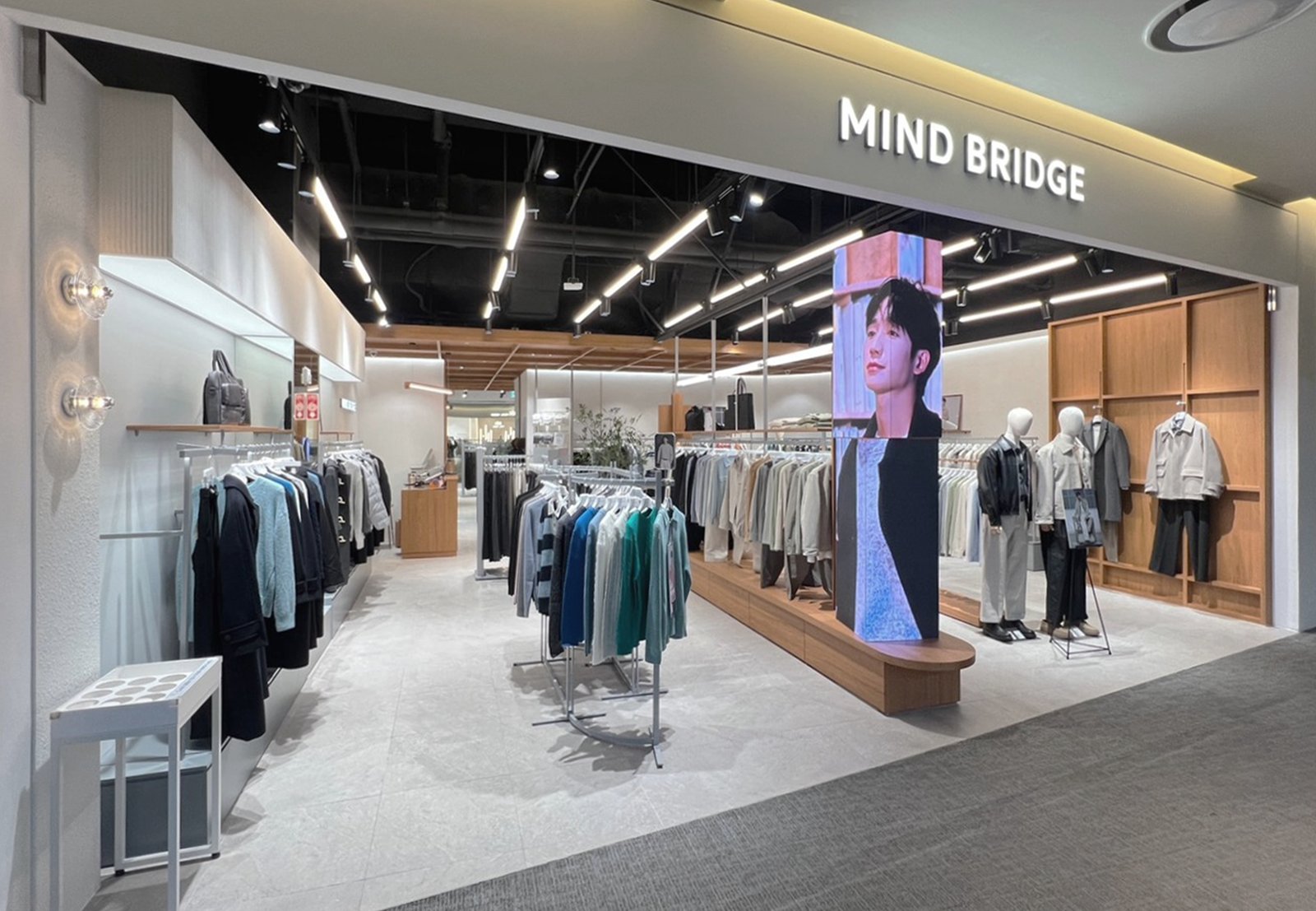 Storefront entrance with portrait media column and clothing rails