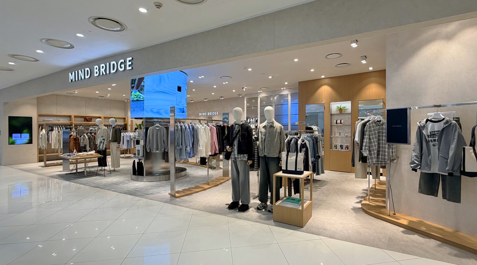 Storefront entrance with mannequins and curved digital display column