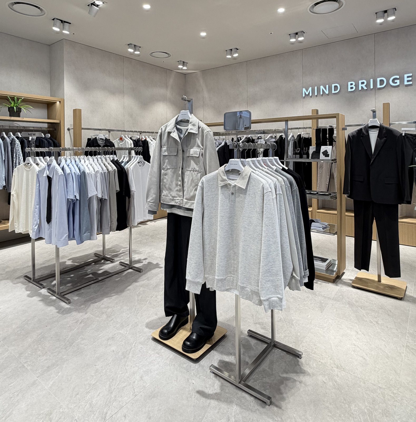Clothing rail with polo shirts and jacket display near signage wall
