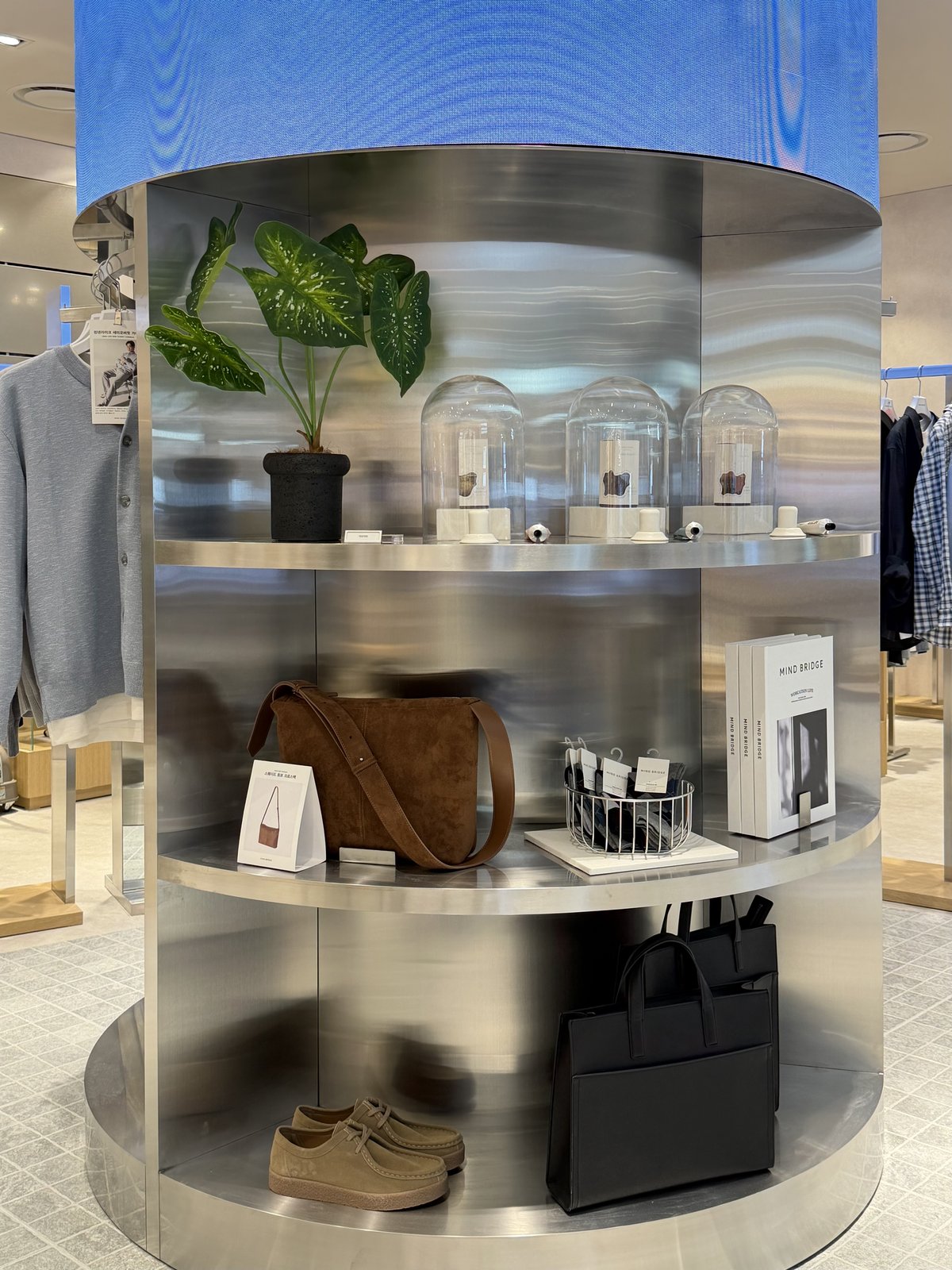 Curved stainless steel shelf display with fragrance domes, bag, and books